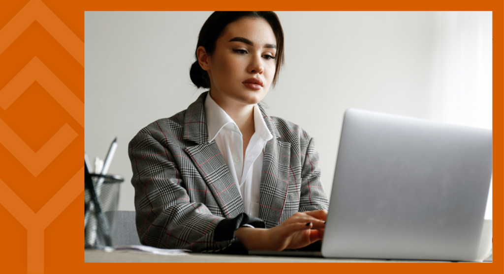 A person sitting at a desk looking at a laptop