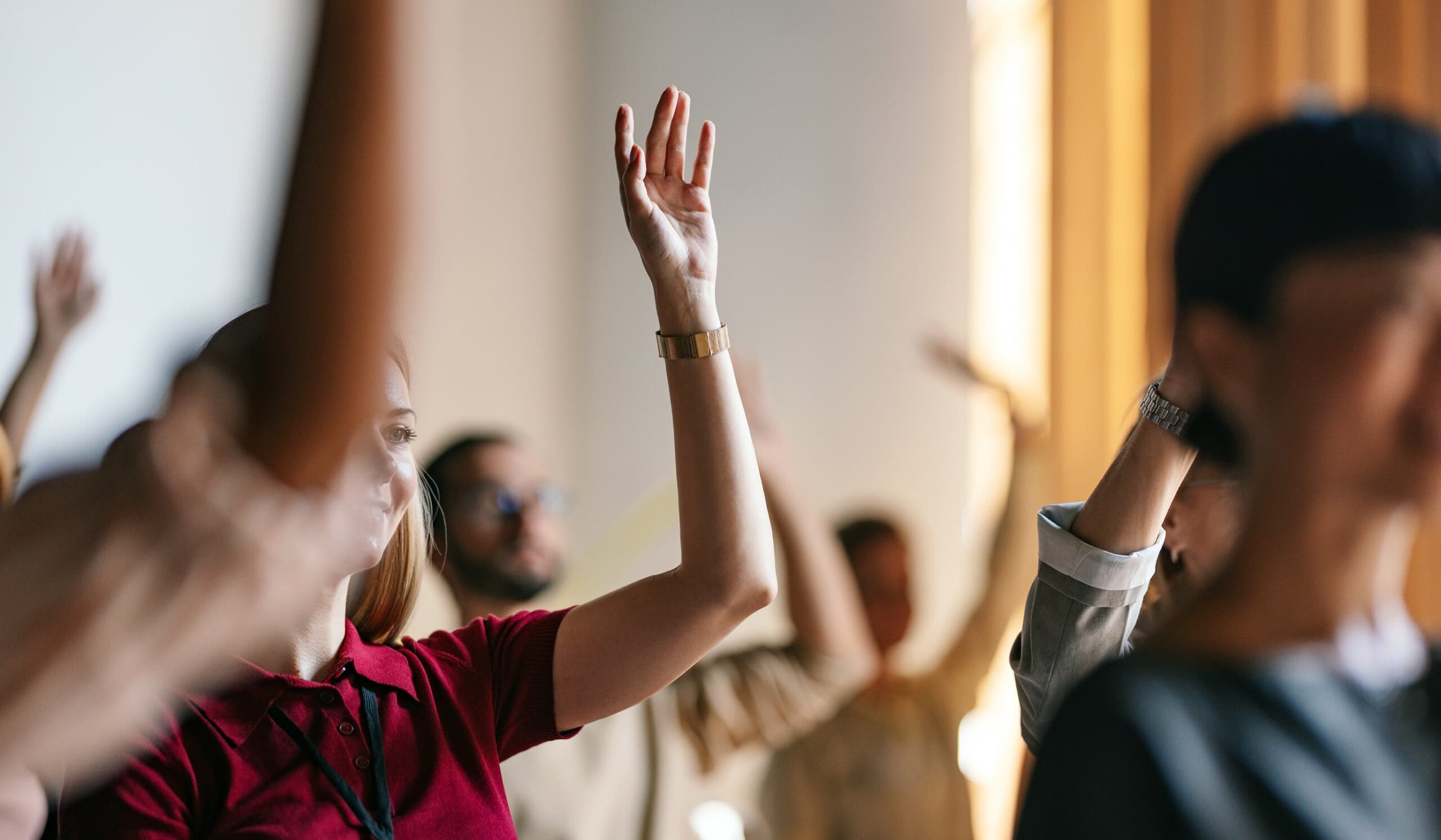 People raising their hands in a meeting room