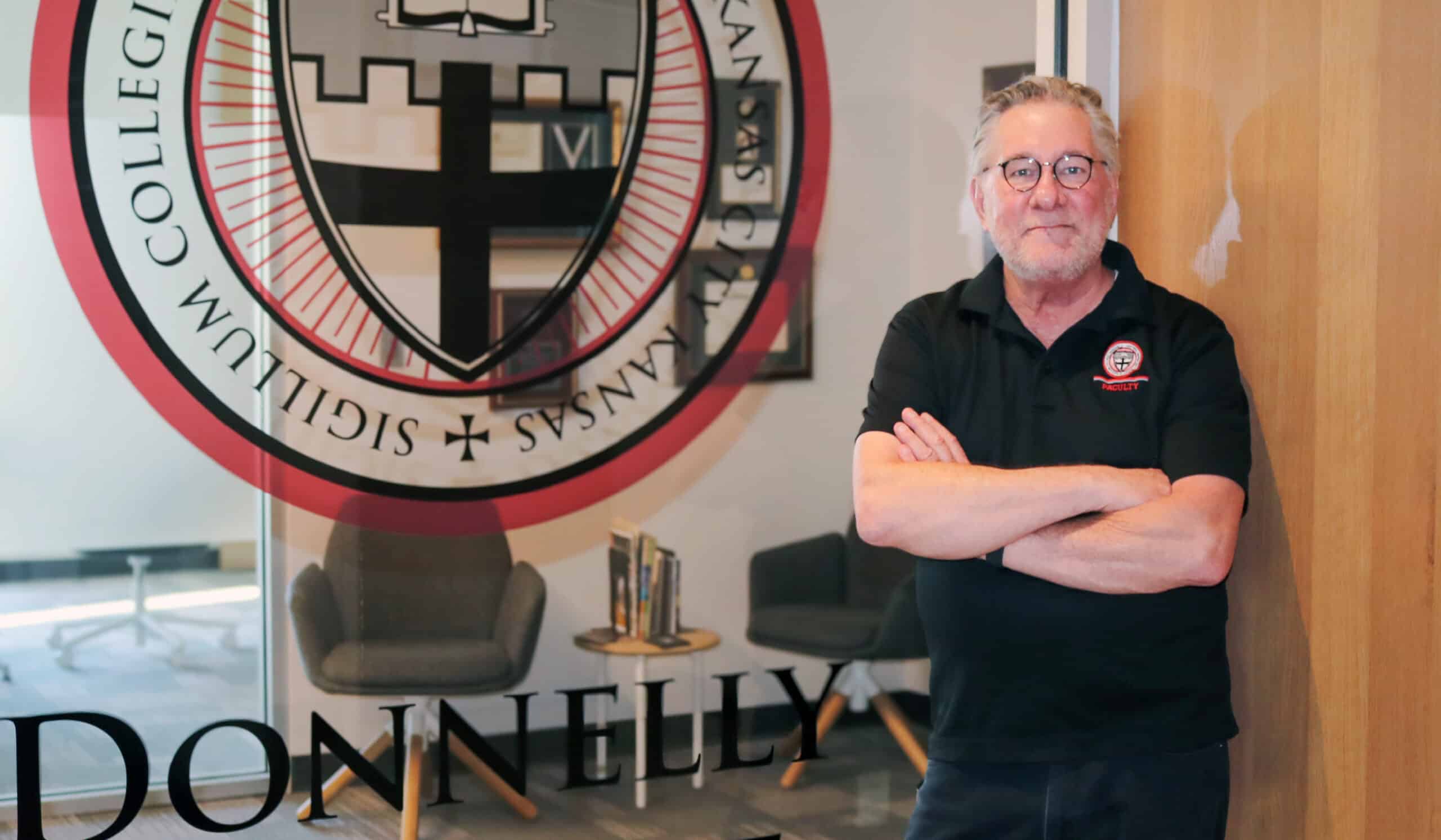 Person from Donnelly College standing in front of their logo